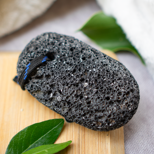 Piedra volcánica para exfoliación en pies en fondo con plantas y madera